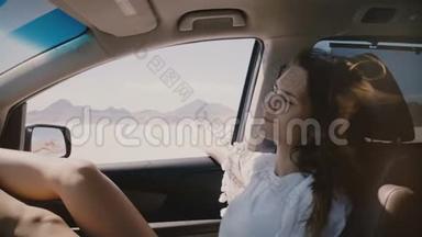 近距离生活方式拍摄的快乐放松的女人在汽车乘客座位上移动沿盐湖沙漠与窗口开放。
